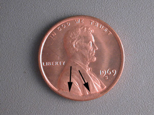 1969 Lincoln penny die cud error showing raised irregular metal blob from major die break on coin rim